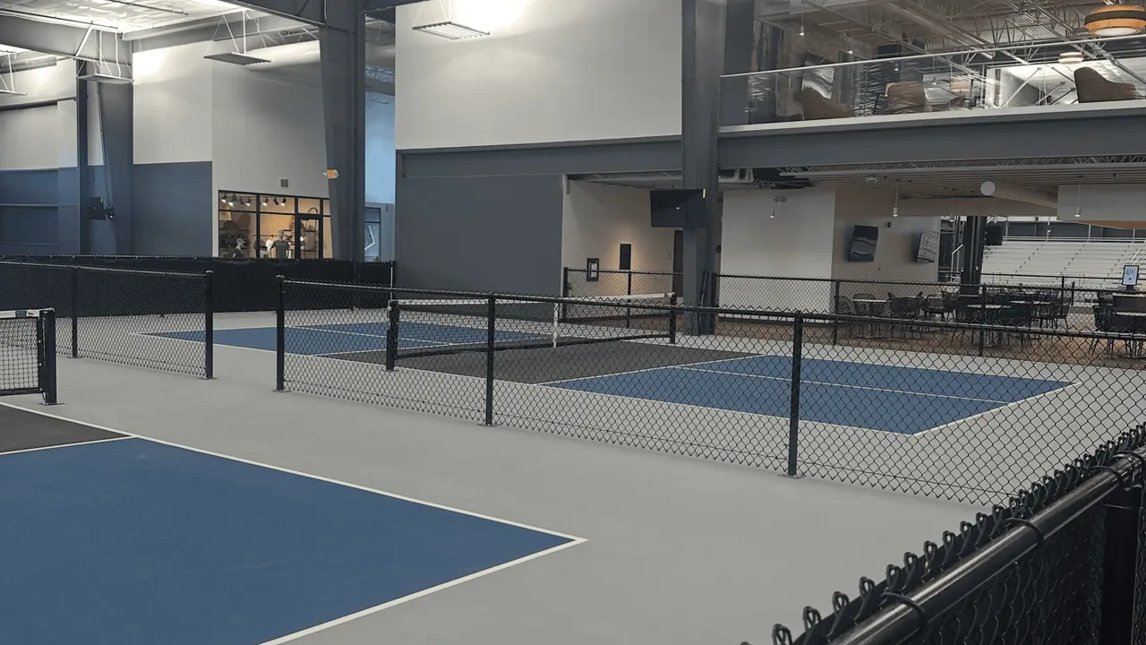 Rows of indoor courts at Greystone with the pro shop and mezzanine lounge behind them