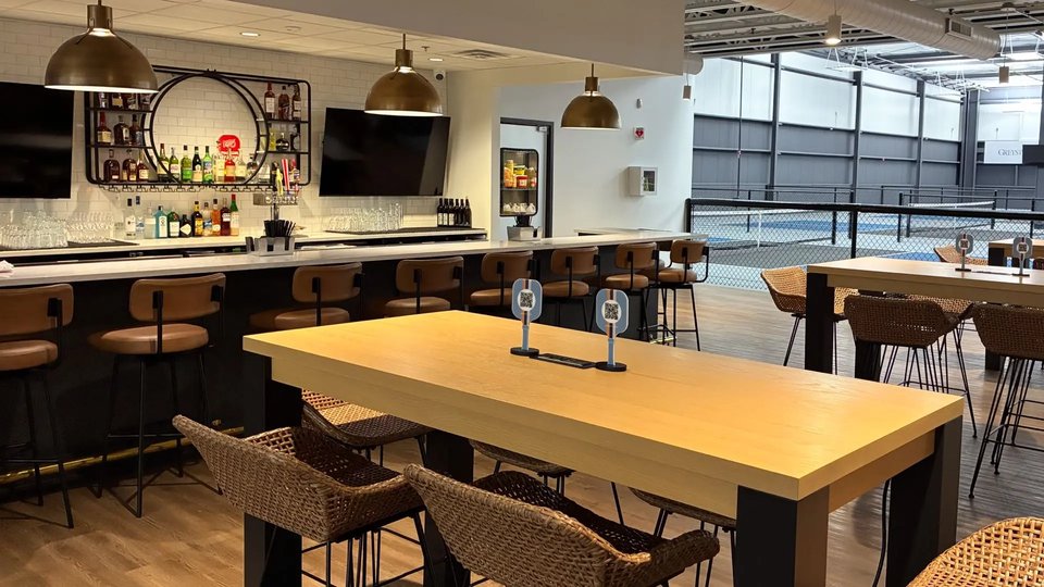 The bar at Greystone Grill with the courts visible through the glass