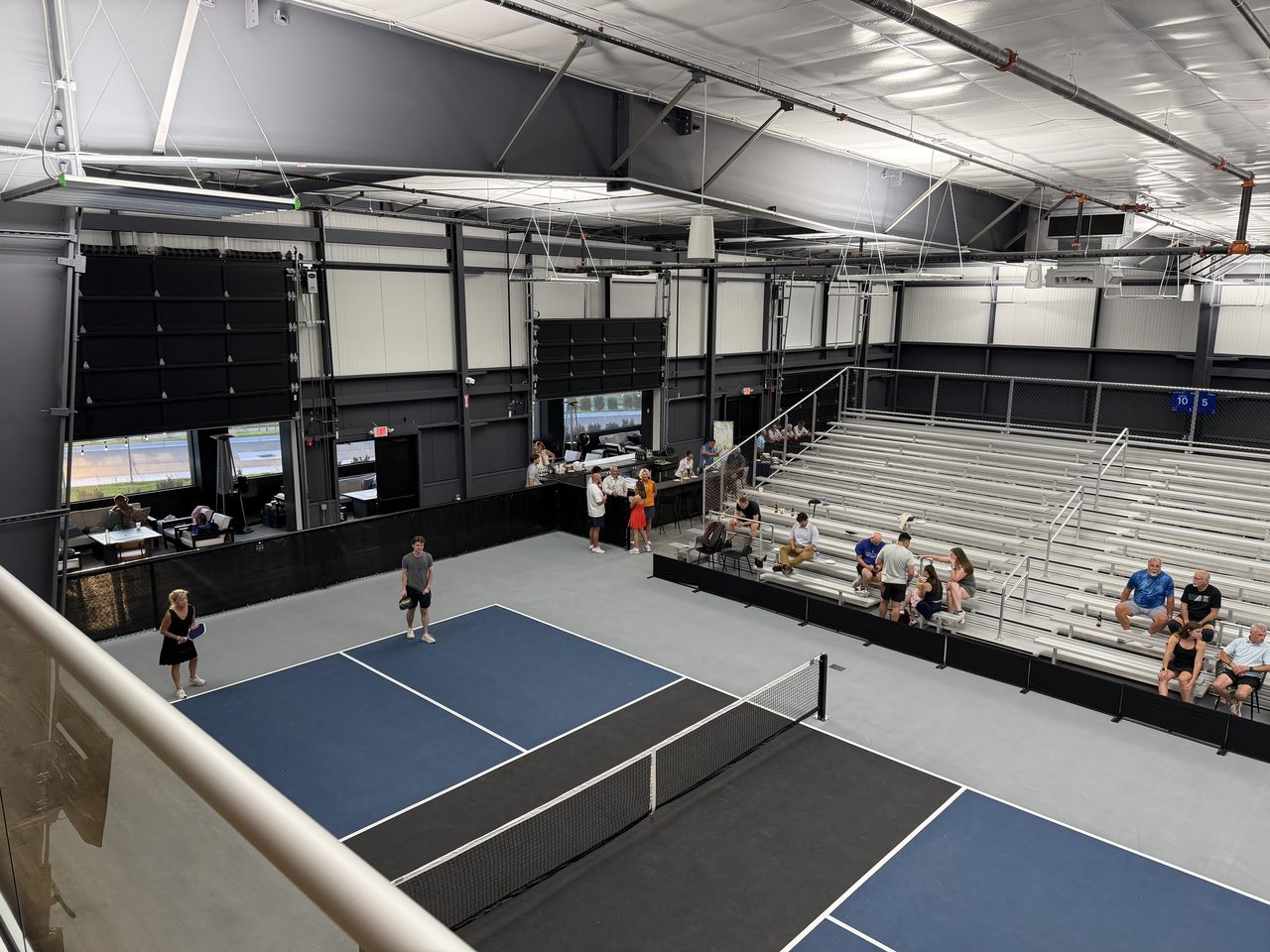 Stadium Court seen from the mezzanine, with spectators in the bleachers watching a match